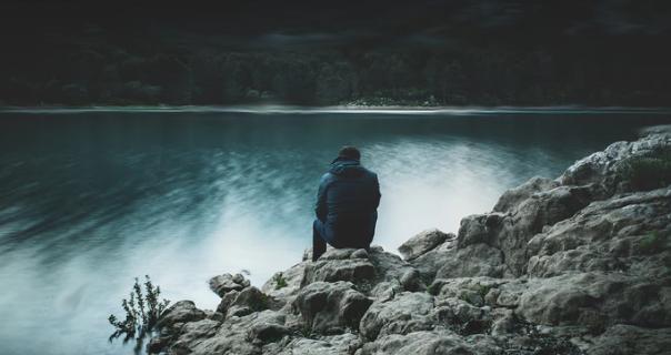 Lonely man sitting by a lake